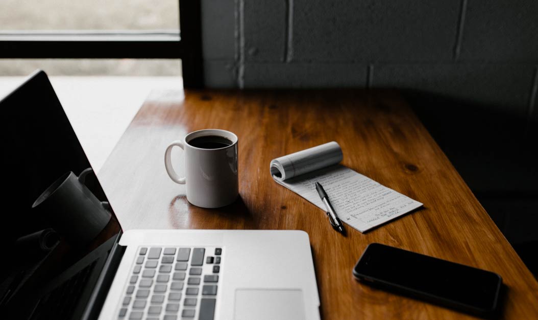 Laptop computer, smart phone, coffee and notepad on a office desk