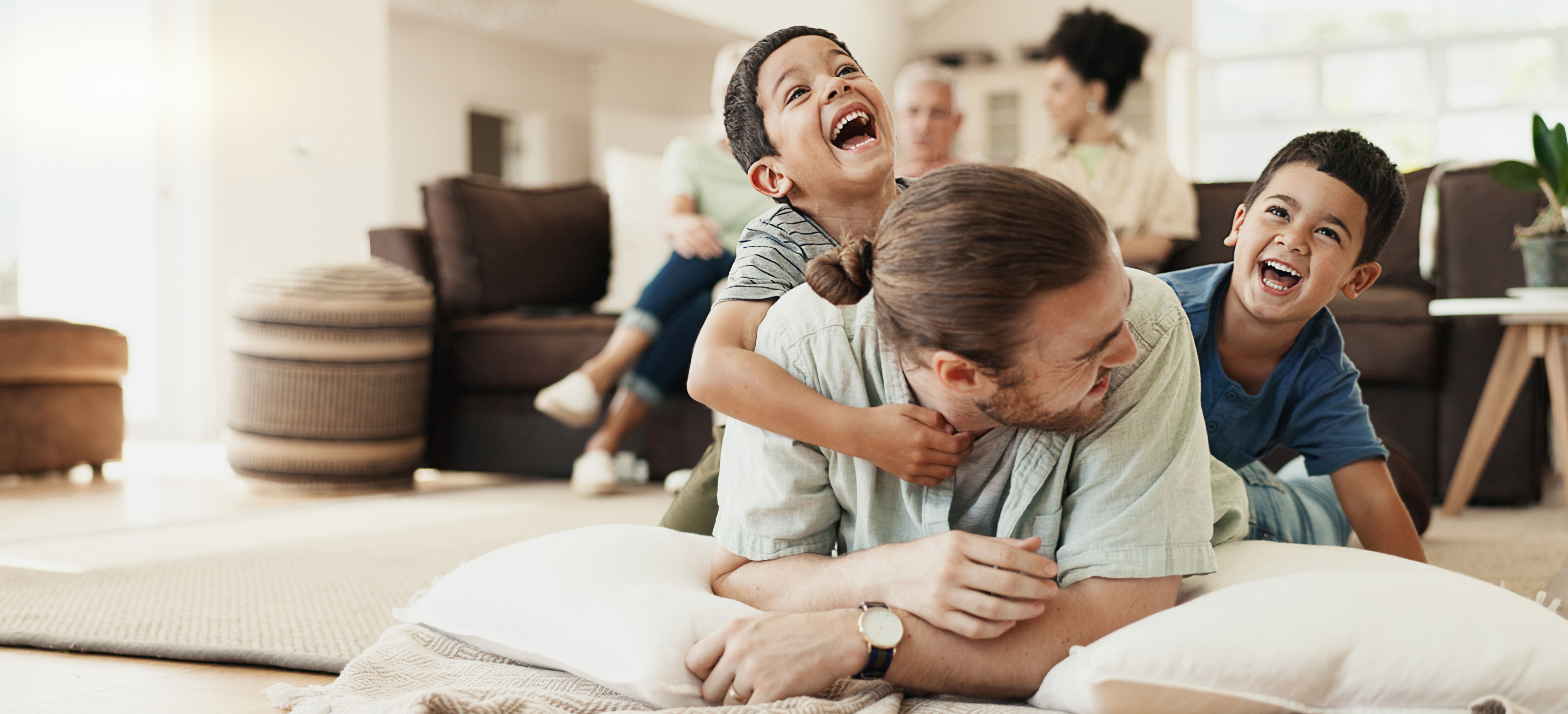 Kids playing with their father in the living room. 