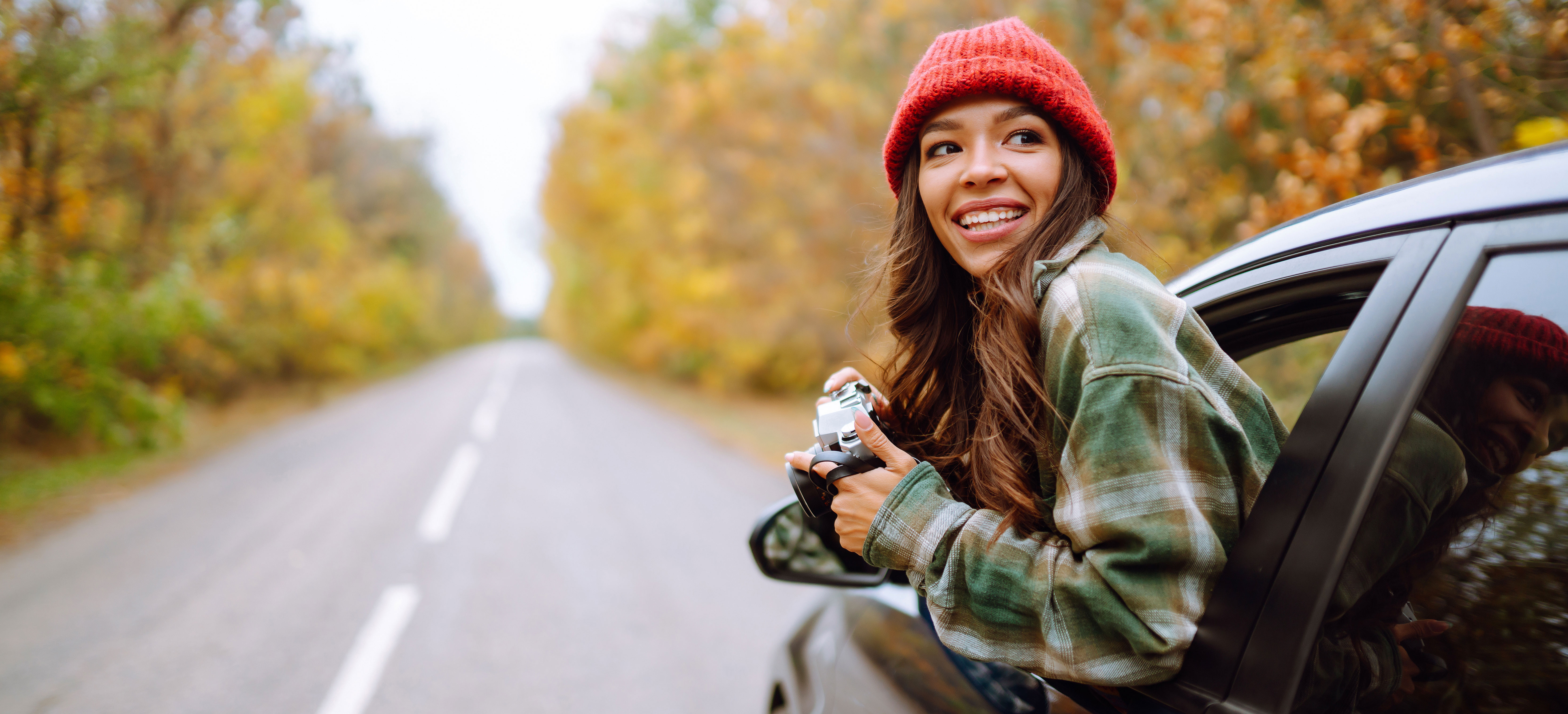 Lady hanging out of a car taking pictures.