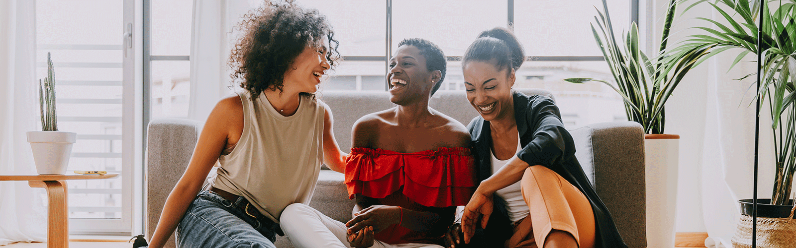 Three women laughing on a couch in a manufactured home. 