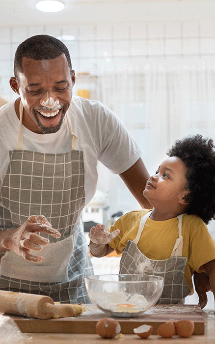 Father and daughter laughing while cooking. 